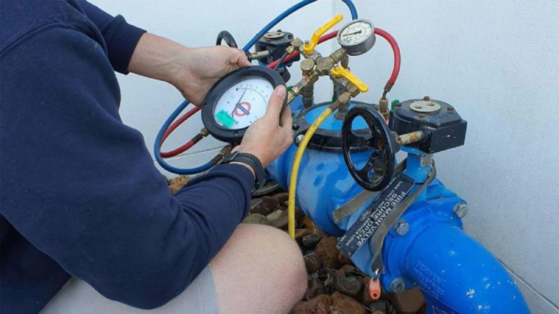 Professional technician performing backflow testing with specialized pressure gauges